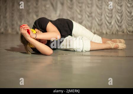 Girl shows emotions on stage. Dance teacher learns to express oneself in motion. Performance of ballerina. Stock Photo