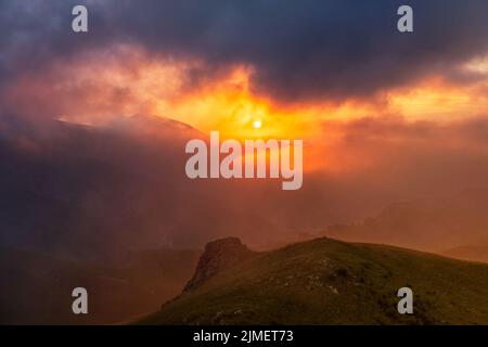 Mountain dramatic sunset in clouds Stock Photo