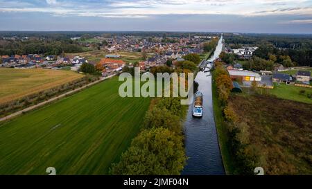 Aerial 4K Bird view shot with a drone of waterway with a barge or freight cargo ship sailing across the natural green orest and Stock Photo