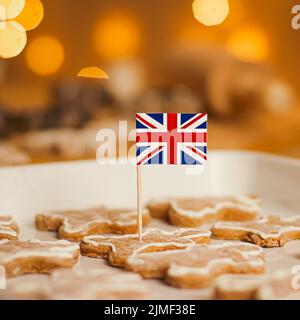 British holiday and Christmas baking concept. Union Jack flag of Great Britain and gingerbread men biscuits in the kitchen in En Stock Photo