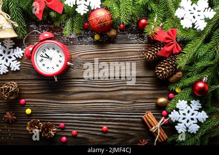 Christmas background of spruce branches with pine cones berries and alarm clock on wooden table with copy-space Stock Photo