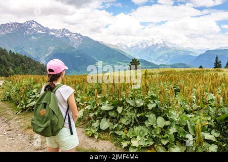 Svaneti landscape on a Summer day. Young tourist woman with a backpack overlooking Caucasus mountain range near Mestia Stock Photo