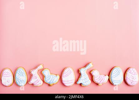 Easter frosted cookies in shape of egg, rabbit and chicken on pink background. Flat lay with copy space. Stock Photo