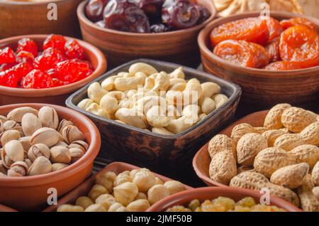 Different nuts and dried fruits in bowls on kitchen table Stock Photo