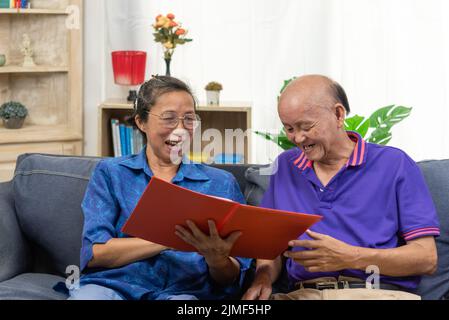 Senior asian couple talking happy planing retirement insurance health care contract on sofa. Stock Photo