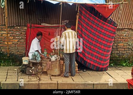 Dhaka, Bangladesh - September 17, 2007: Seller with customer at poor snack stand on the sidewalk Stock Photo