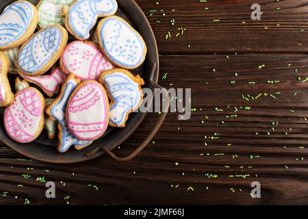 Sugar sprinkles and metal tray with Easter frosted cookies in shape of egg chicken and rabbit on wooden table background. Flat l Stock Photo
