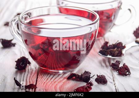 Closeup view at two tea cups and dry hibiscus petals on white wooden table background Stock Photo