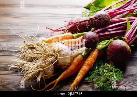 Fresh organic beetroots green garlic and carrots on kitchen wooden rustic table close up view Stock Photo