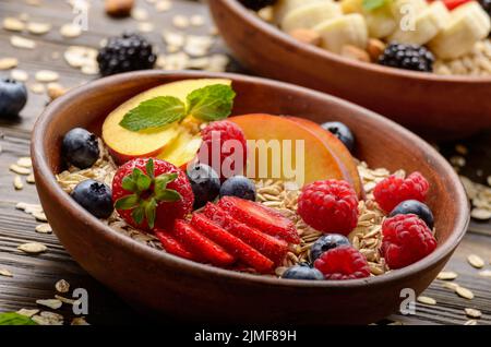 Fruit healthy muesli with peaches strawberry almonds and blackberry in clay dish on wooden kitchen table Stock Photo