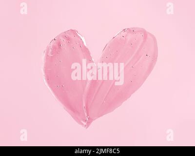 Transparent cosmetic gel heart shape on pink bg