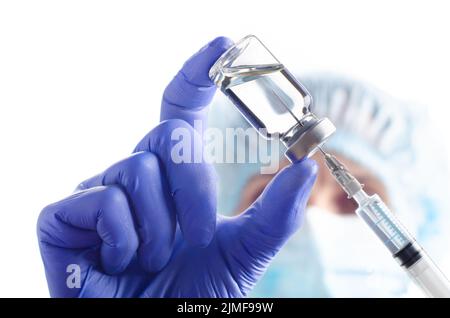 Caucasian female doctor in protective gloves and mask fill syringe with medicine for injection