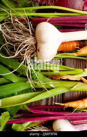 Vegetarian background of fresh organic beetroots green garlic and carrots on kitchen wooden rustic table Stock Photo