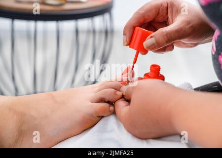 Close up photo of nail polishing. Woman get pedicure treatment in beauty salon. Beauty and cosmetic concept. High quality photo. Stock Photo