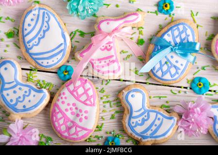 Homemade Easter cookies in shape of eggs chicken and rabbit on white wooden kitchen table flat lay closeup view. Space for text Stock Photo