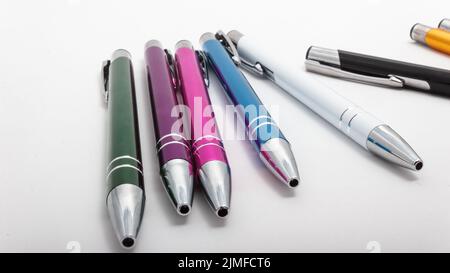 A closeup shot of a row of different-colored pens on a white table Stock Photo