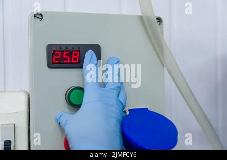 Woman working in industry, adjusting tank thermostat Stock Photo