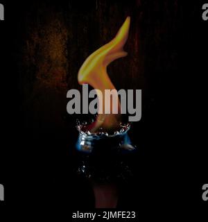 an orange flame emerging from a water splash on a black background, UK Stock Photo