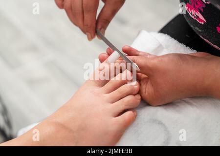 Close up photo of toenail filing. Woman get professional pedicure treatment in beauty salon. Beauty and cosmetic concept. High quality photo Stock Photo