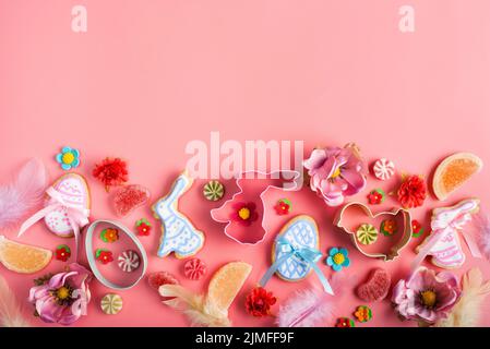 Easter cookies candies sugar sprinkles and cutters on pink background. Space for text Stock Photo