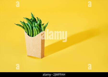 Fresh green beans in fast food paper box on bright yellow background with copy space Stock Photo