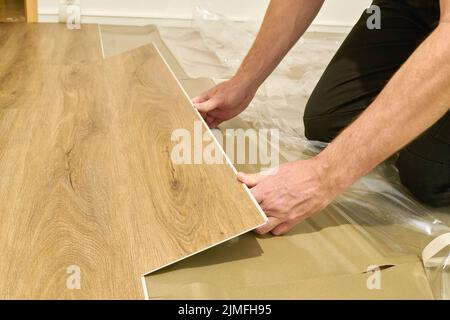 Craftsman renovating an apartment and laying a click vinyl floor covering Stock Photo