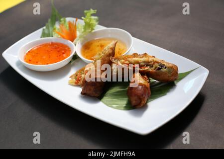 Fried spring rolls on a white plate and spicy sauce Stock Photo