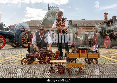 Kidderminster, Worcs, UK. 6th Aug, 2022. Steam enthusiast Michael Pryce shows off his pride and joy 1:3 scale miniature steam traction engine 'Smokey Joe' with Jim Parker at the Severn Valley Railway's Vintage Transport Extravaganza at Kidderminster, Worcestershire. The annual event has vintage motor vehicles as well as steam engines. Credit: Peter Lopeman/Alamy Live News Stock Photo