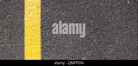 Asphalt texture with a yellow line on the left side. Road surface with markings. Stock Photo