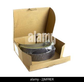 Brown cardboard box with car brake pads isolated on white background. Spare parts for transport. Stock Photo