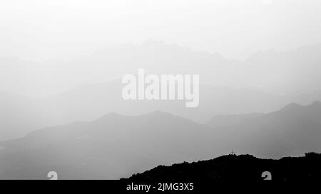 Mountain layers in black and white. Cross profile. Atmosphere with fog, clouds. Italy. Europe. Stock Photo