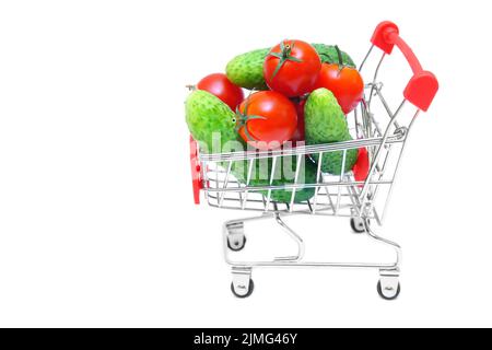 Miniature shopping trolley full of cucumbers and cherry tomatoes isolated on white background. Fresh vegetables supermarket delivery concept. Stock Photo