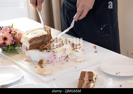 Detail of waiter cutting wedding cake during a marriage celebration party Stock Photo