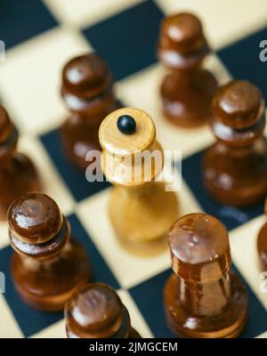 Chess pieces stand on a chessboard. Pawns surrounded the queen Stock Photo