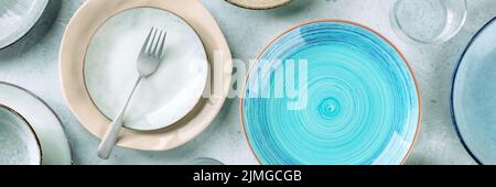 Modern tableware panorama with a blue plate, a fork, and many other clean dishes Stock Photo