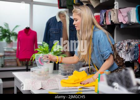 The girl is looking for suitable accessories for the chosen yellow fabric. Stock Photo