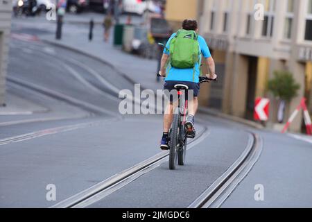 Radfahrer von hinten zwischen Straßenbahnschienen in Gmunden, Österreich - Cyclists from behind between tram tracks in Gmunden, Austria Stock Photo