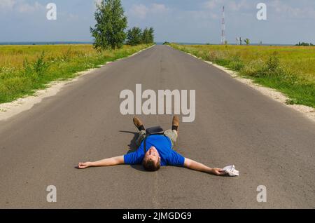 Happy man is lying on the road. Finally, a vacation Stock Photo