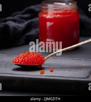 Fresh grainy red caviar in a glass jar on a wooden table Stock Photo
