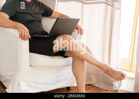 Working from home on the laptop. Wearing casual comfort outfit in home office. Stock Photo