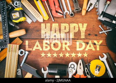 Happy Labor Day flat lay. Construction tools and text on wooden table, top view. United States America holiday celebration Stock Photo