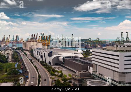 The huge busiest logistic port in Singapore, plenty of cranes to move containers, huge cargo ships in the background, shopping m Stock Photo