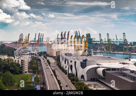 The huge busiest logistic port in Singapore, plenty of cranes to move containers, huge cargo ships in the background, shopping m Stock Photo