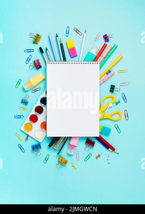 Online study, drawing, distantly painting class. Notebook, colorful stationery, supplies for drawing and craft. Empty notepad sketchbook sheet, shool supplies on blue. Vertical. Copy space, flatlay Stock Photo
