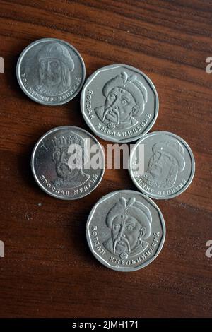 Ukrainian kopecks, small change in the amount of one 1, two 2, five 5 hryvnias are located on a dark brown table. Stock Photo