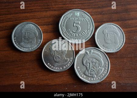 Ukrainian kopecks, small change in the amount of one 1, two 2, five 5 hryvnias are located on a dark brown table. Stock Photo