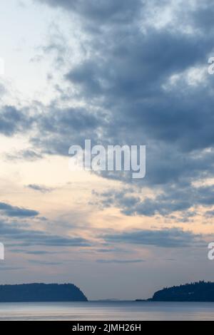 Dramatic Sun setting behind storm clouds over the Puget Sound Stock Photo