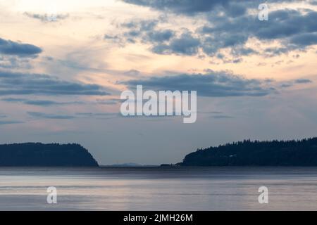 Dramatic Sun setting behind storm clouds over the Puget Sound Stock Photo