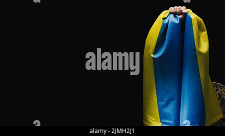 Ukrainian soldier holds a flag of the independent state of Ukraine. Steadfastness and courage of the people in the fight against Stock Photo