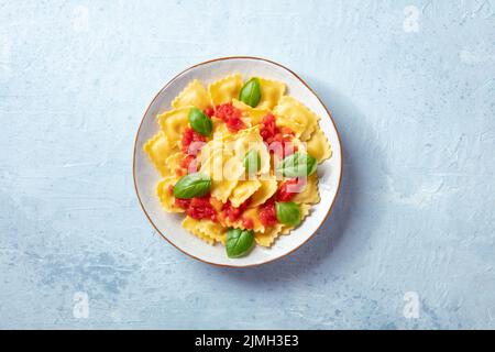Ravioli with tomato sauce and fresh basil on a plate, shot from the top Stock Photo